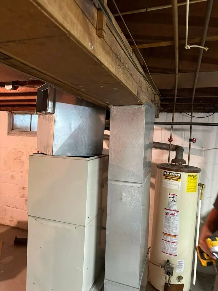 A man is standing in a basement next to a water heater.