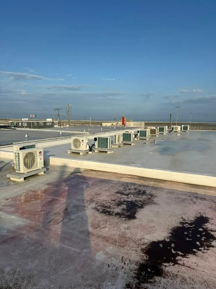 There are a lot of air conditioners on the roof of a building.
