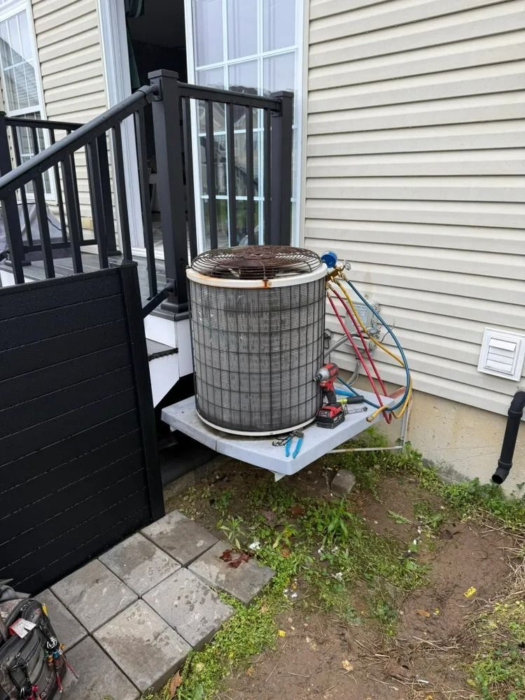 An air conditioner is sitting on a shelf outside of a house.