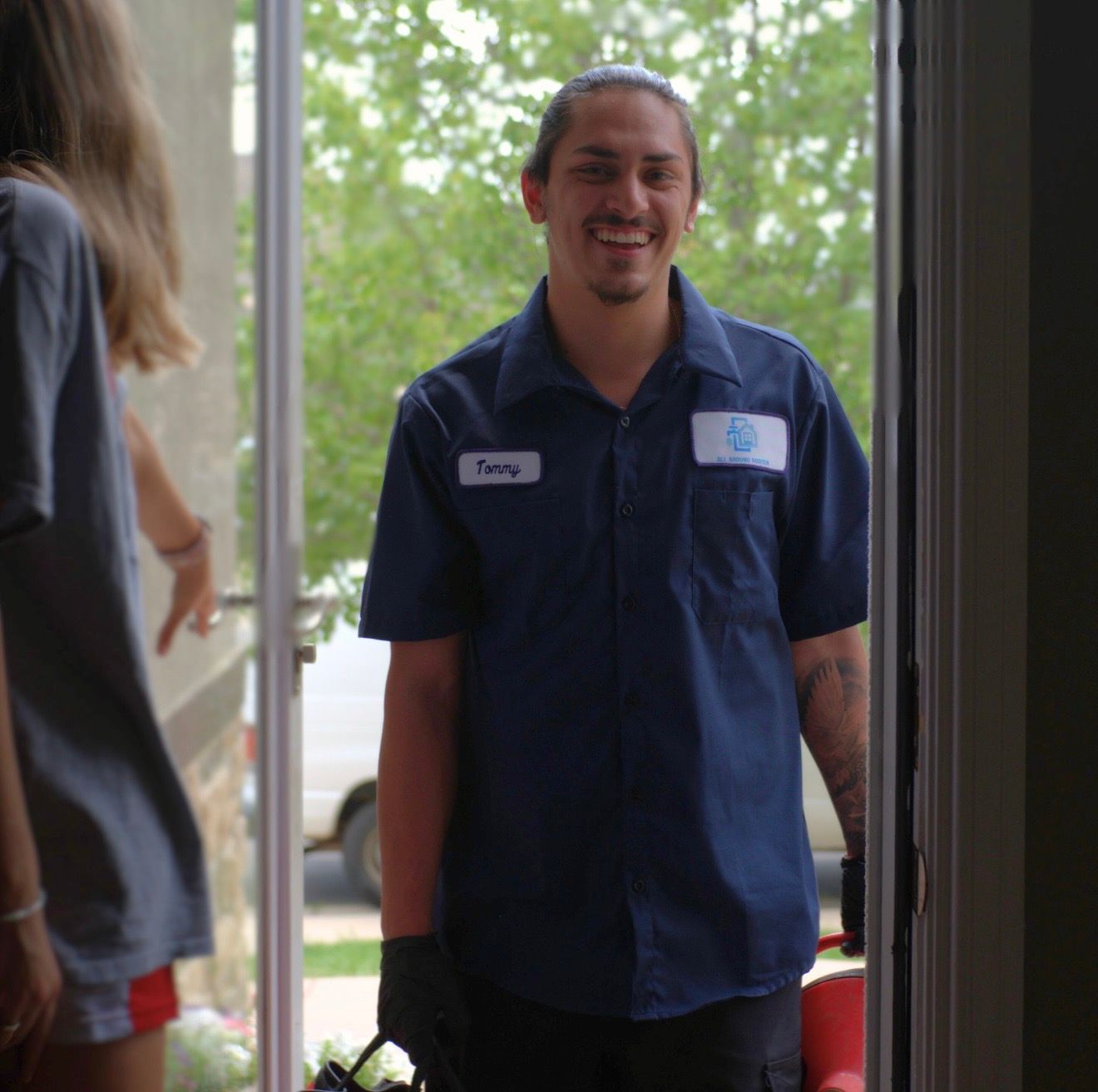 A chrome faucet runs water into a stainless steel double sink in a modern kitchen with white cabinets and tile.