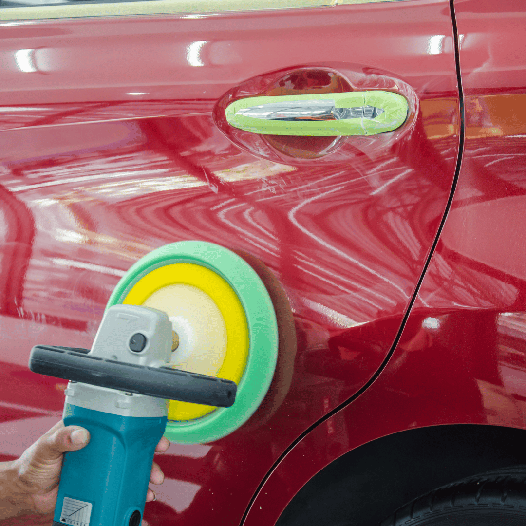 A person is polishing a red car with a machine.