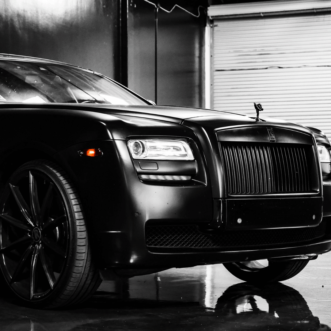 A black and white photo of a rolls royce parked in a garage.