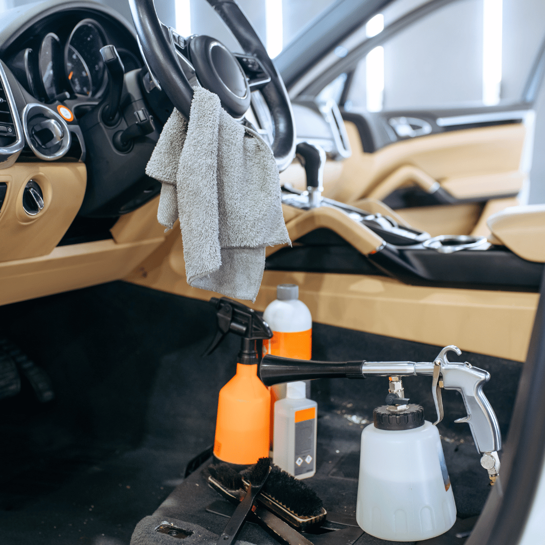 A car is being cleaned with spray bottles and brushes