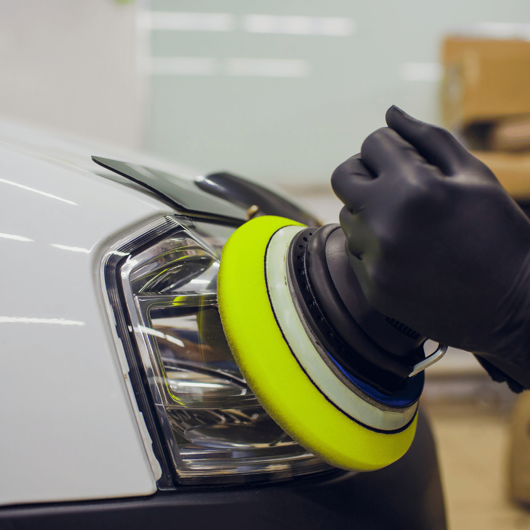 A person is polishing the headlight of a white car