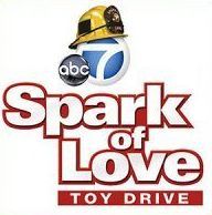 The logo for spark of love toy drive with a fireman 's helmet on it.