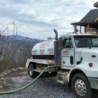 A white Jarrett's septic service truck parked on a gravel drive with a mountain view in the background.