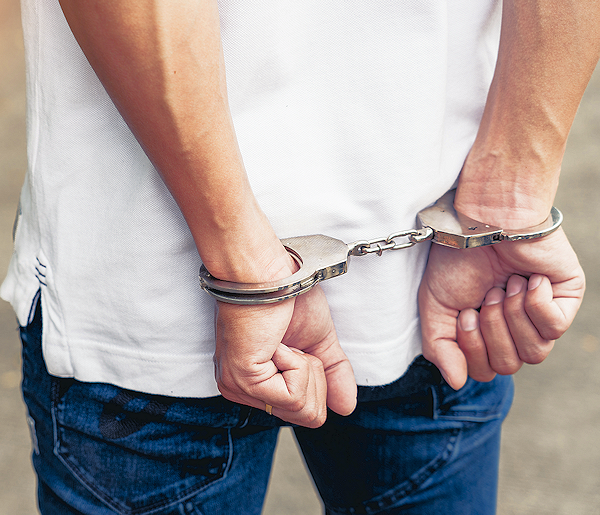 Close-up of a man's hands handcuffed together behind his back.