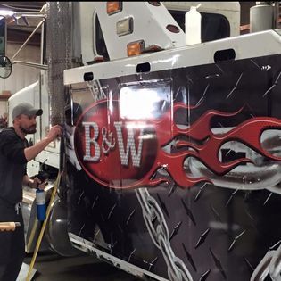 A man is working on a b & w truck