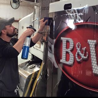 A man is spraying a sign that says b & i