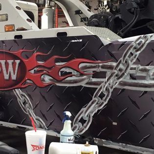 A tow truck with flames and chains painted on it