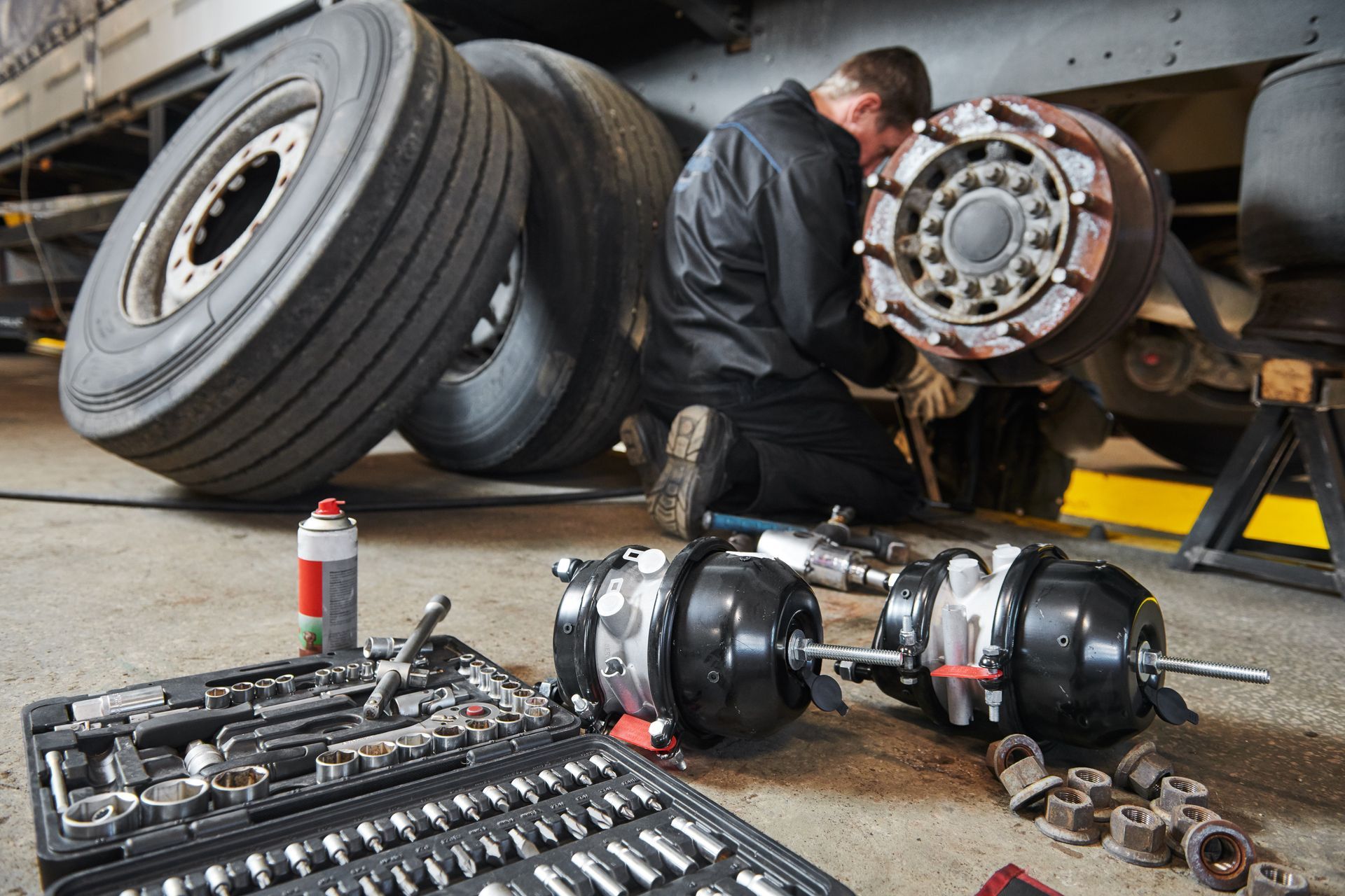 A mechanic works with brakes in a truck workshop.