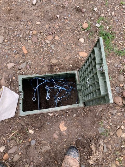 A person is standing next to a green box on the ground.