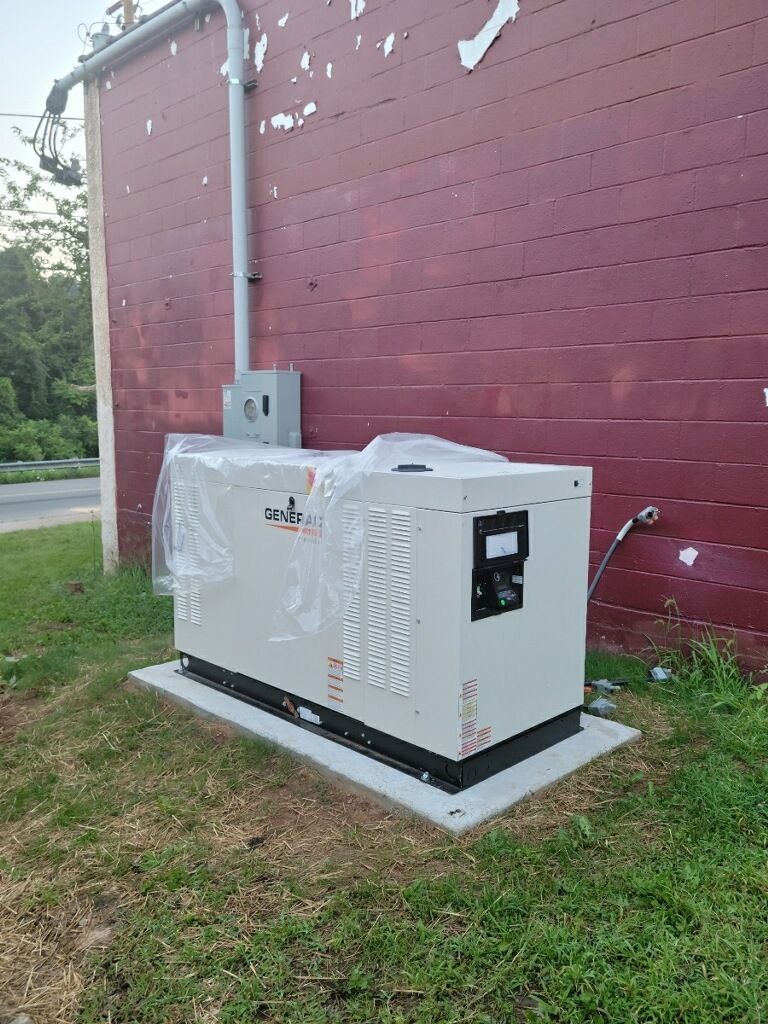 A white generator is sitting in front of a red brick building.