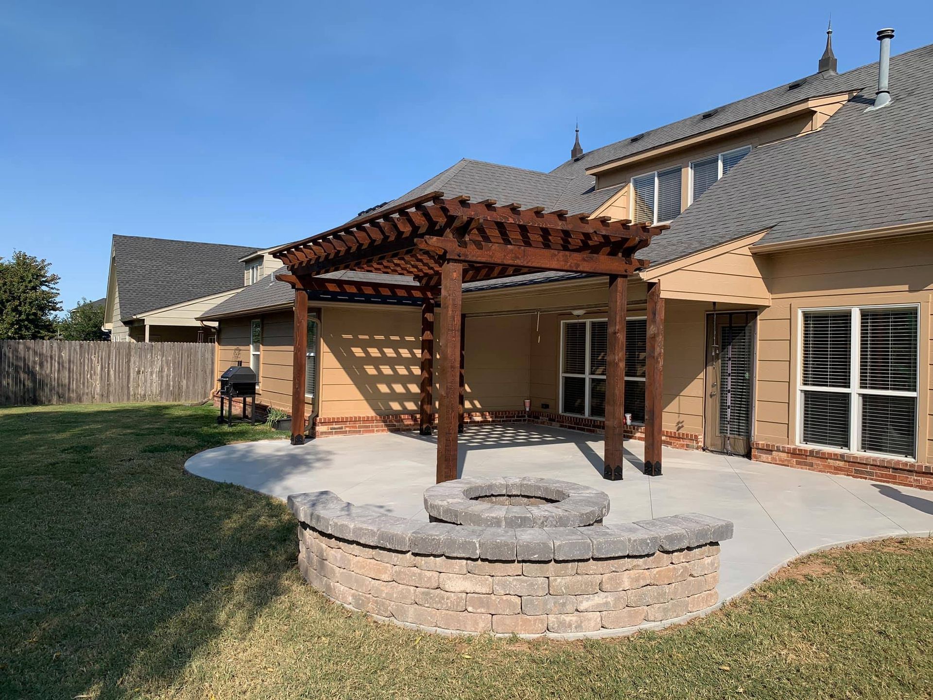 A house with a pergola and a fire pit in the backyard.