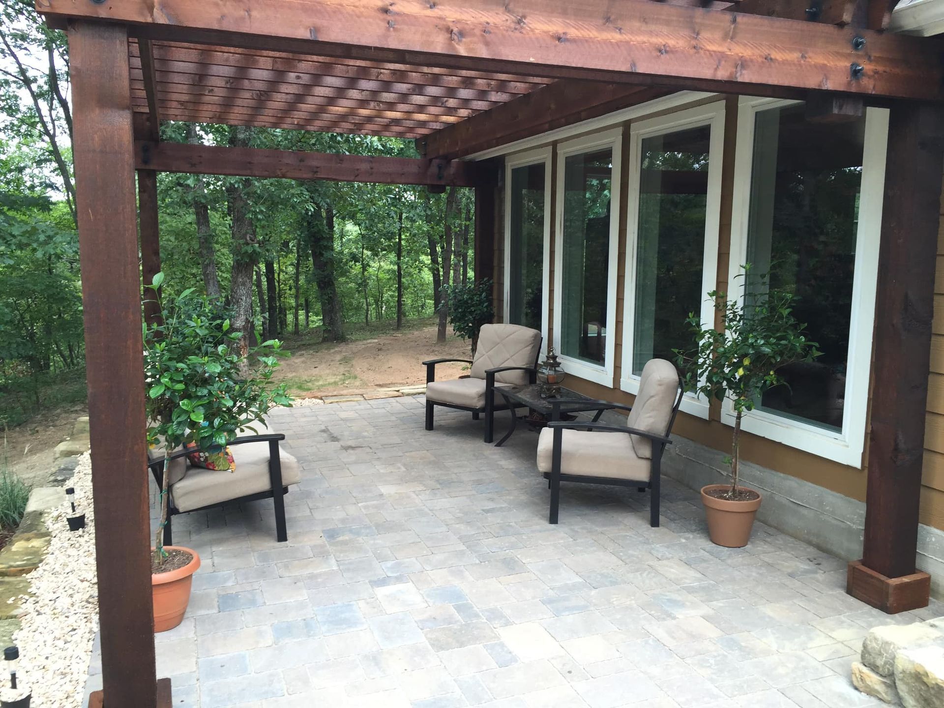 A patio with chairs and a table under a pergola.