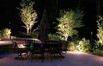 A patio with a table and chairs and umbrellas at night.