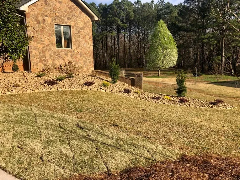 A brick house with a large lawn in front of it surrounded by trees.