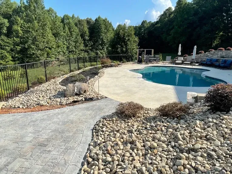 A large swimming pool is surrounded by rocks and trees.