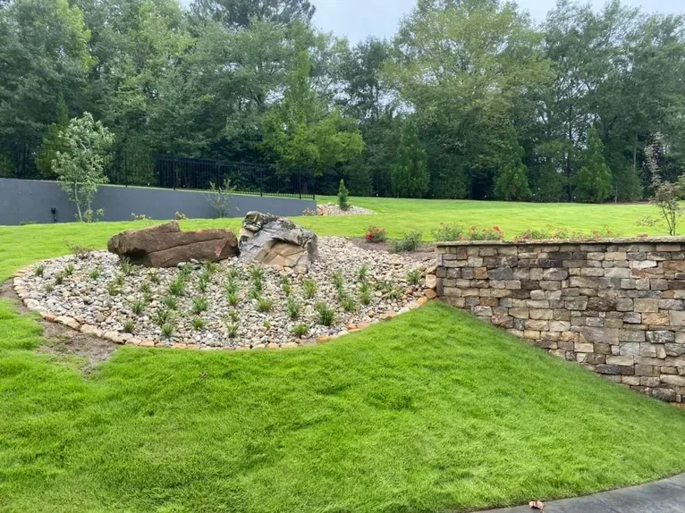 A stone wall in the middle of a lush green field.
