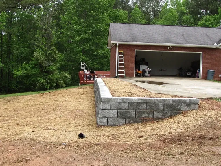 A brick garage with a concrete driveway in front of it.
