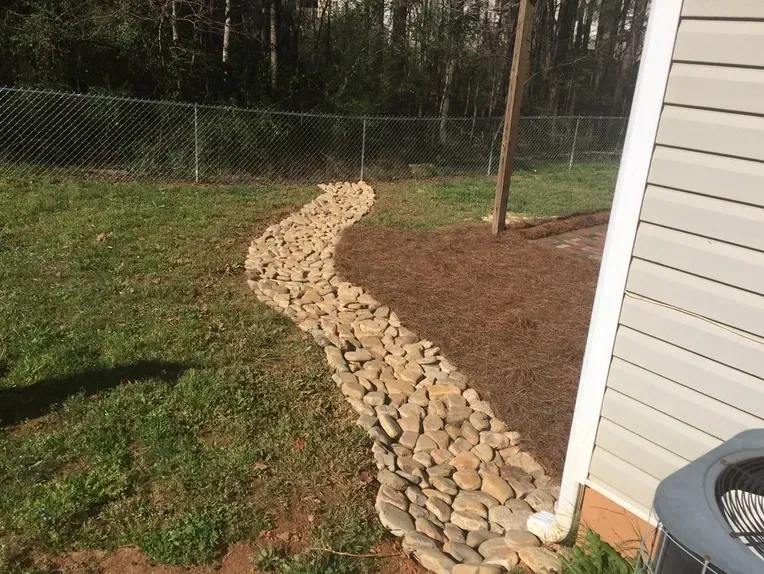 A walkway made of rocks is next to a house.