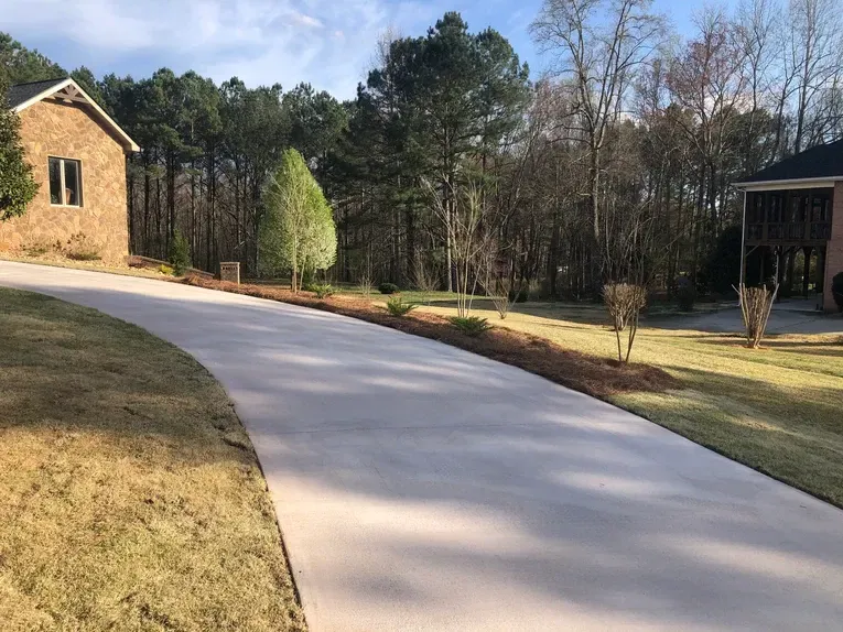 A driveway leading to a brick house in the woods.