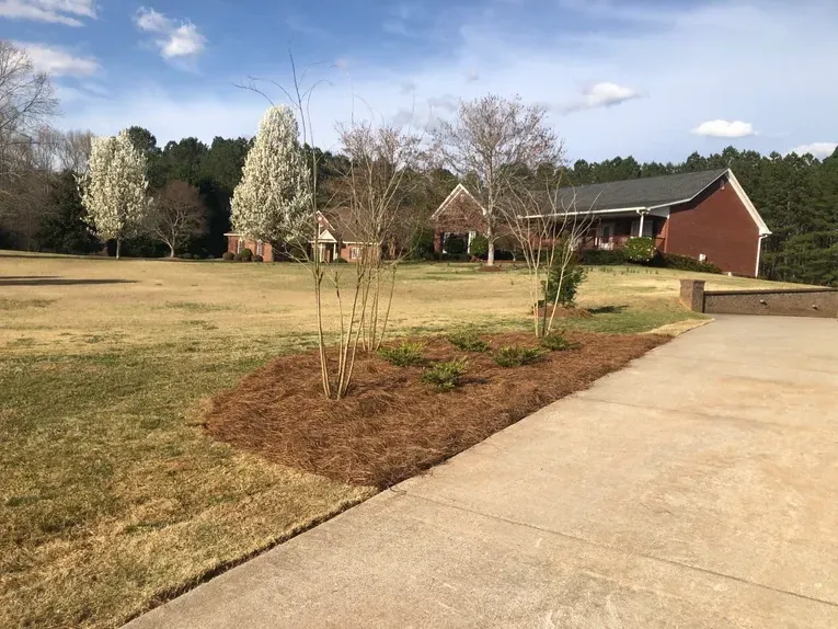A brick house sits in the middle of a lush green field.