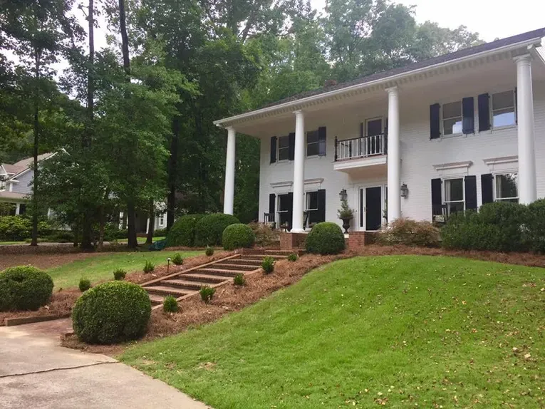 A large white house with a lush green lawn in front of it.