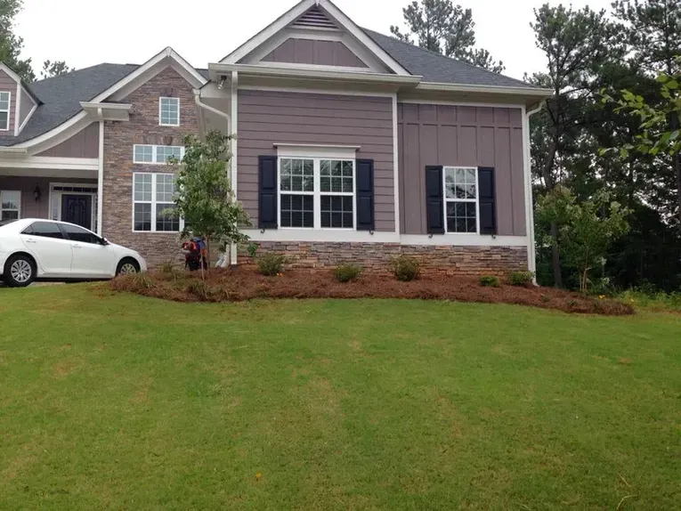 A white car is parked in front of a large house.