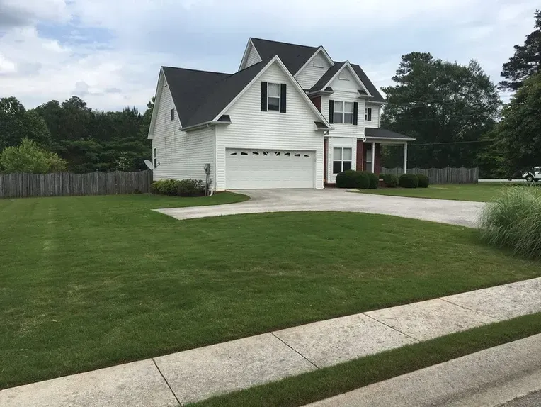 A large white house with a lush green lawn in front of it.