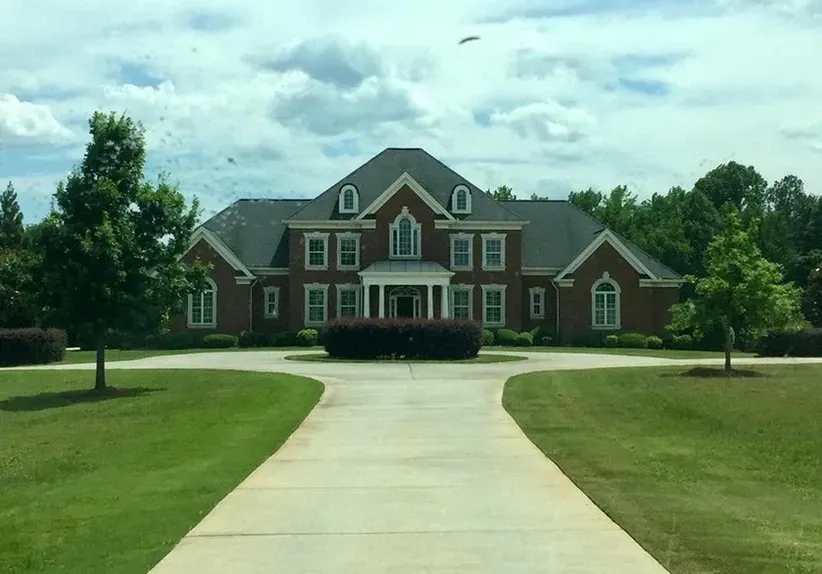 A large brick house with a driveway leading to it.