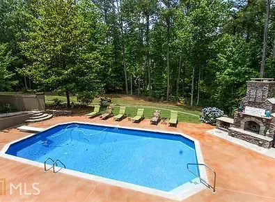 A large swimming pool with a fireplace in the backyard.