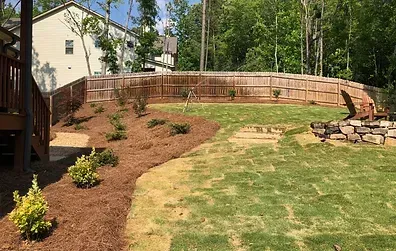 A backyard with a wooden fence and a lush green lawn.