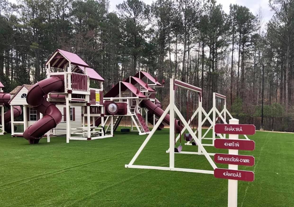 A playground with a slide , swings , and a sign that says ' agility course ' on it.