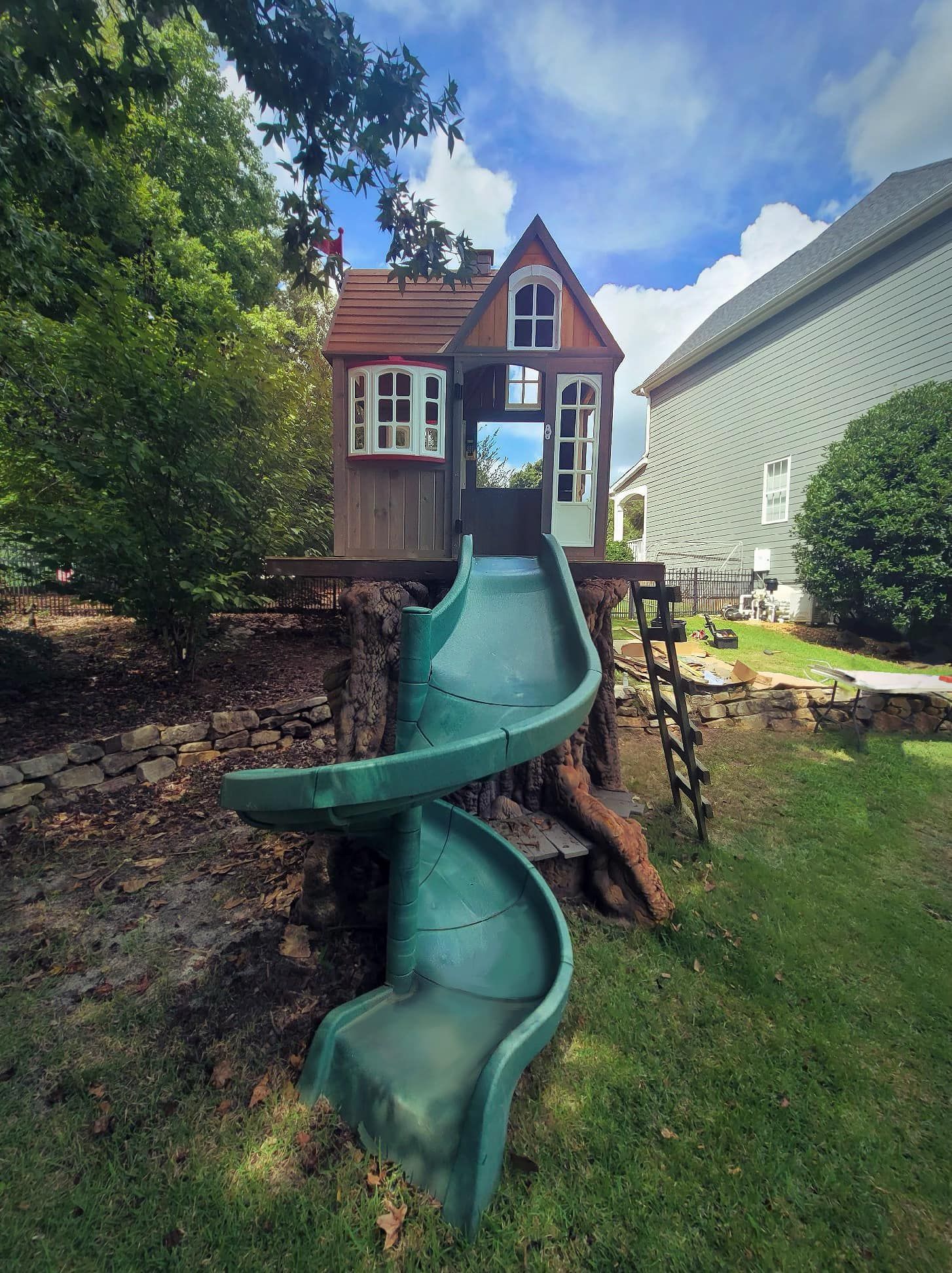 A tree house with a green slide attached to it.