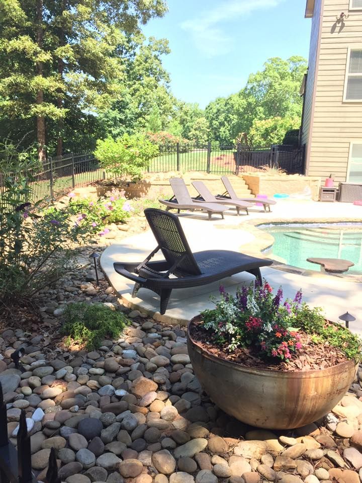 A large bowl of flowers is sitting next to a swimming pool.