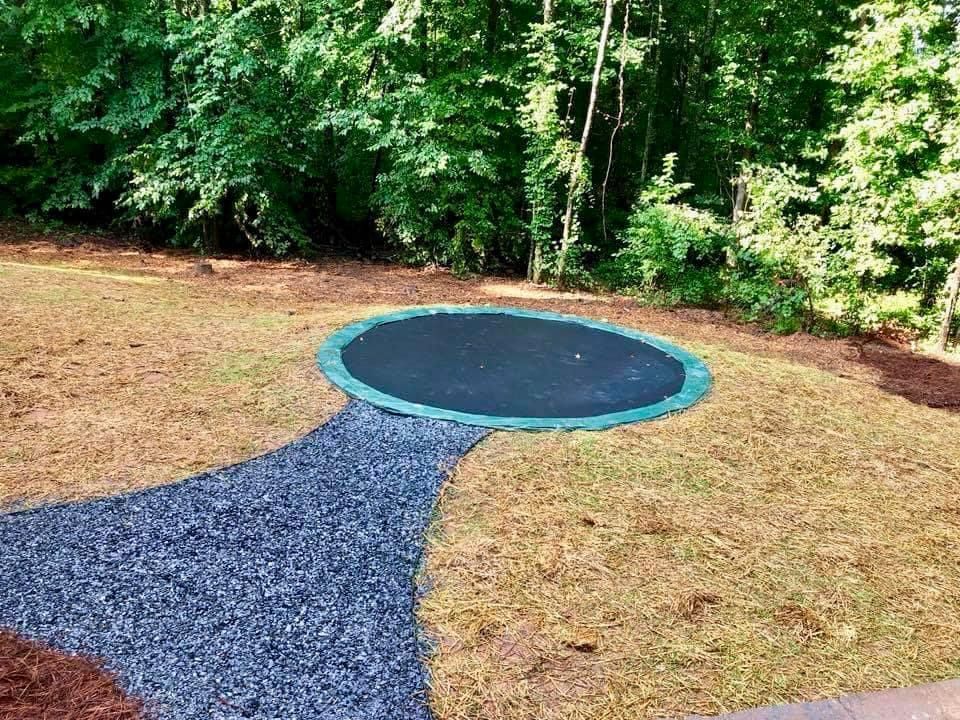 A trampoline is sitting in the middle of a lush green field.
