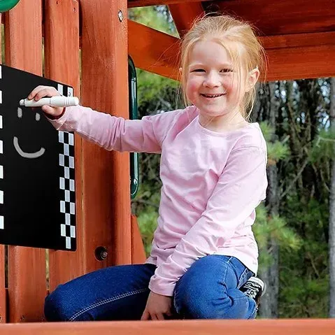 A little girl is writing on a blackboard with a marker.
