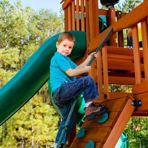 A young boy in a blue shirt is sitting on a slide on a playground