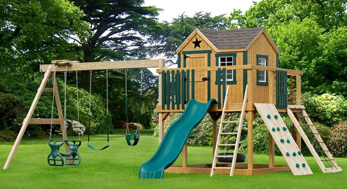 A wooden tree house with a slide and swings.