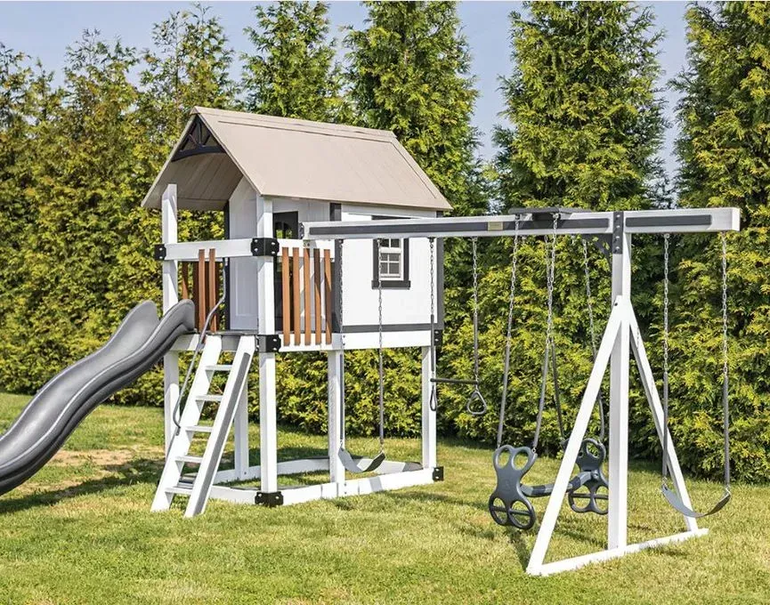 A white swing set with a slide and swings in a backyard.