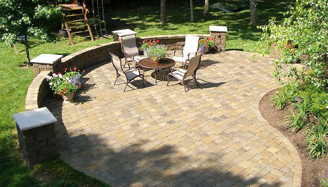 A patio with a table and chairs in a backyard.