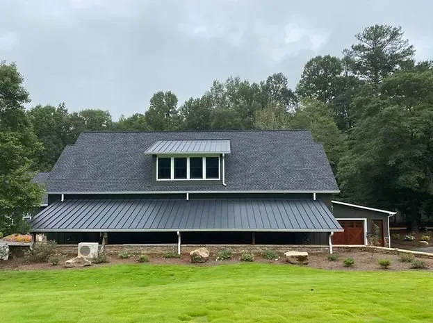 A large house with a gray roof is sitting on top of a lush green field.