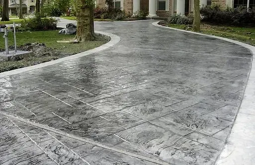 A concrete driveway leading to a house with a mailbox on the side of it.
