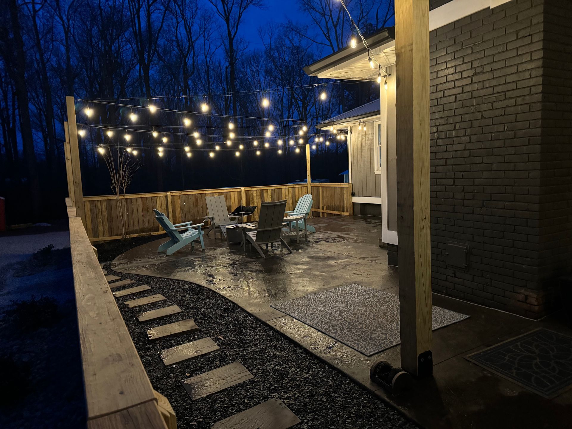 Outdoor patio with string lights, seating area, pathway, and dark night setting.