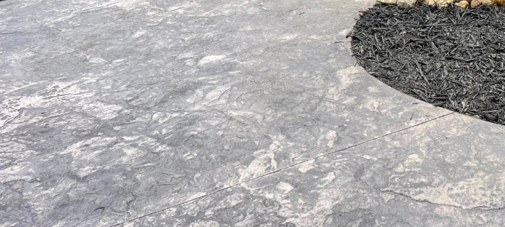 Gray stone patio with an adjacent dark mulch bed.