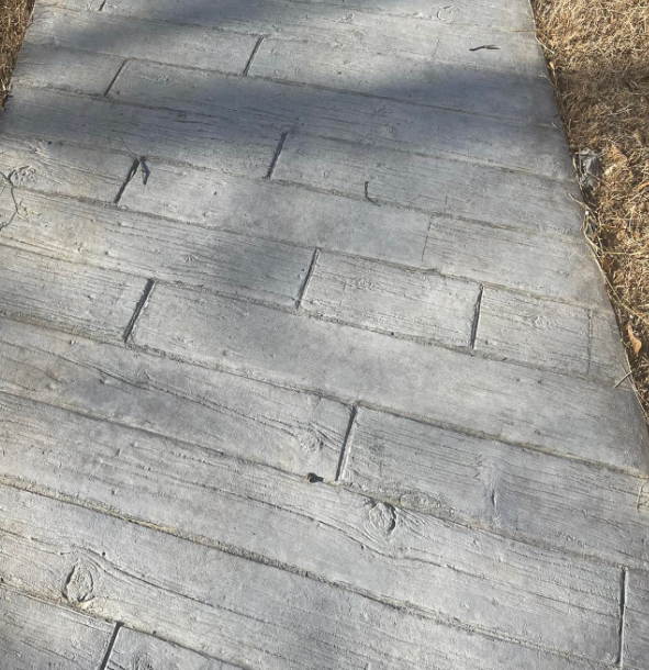 Concrete walkway with a wood plank pattern, gray, outdoors.