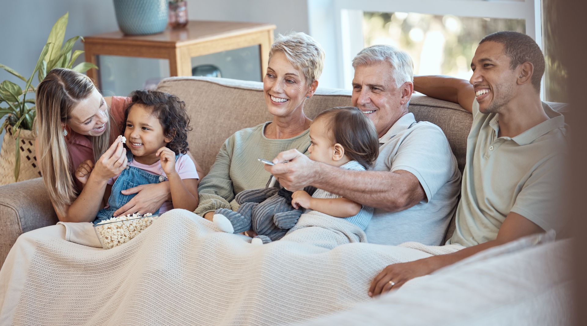 Family sitting together on a couch, eating popcorn.