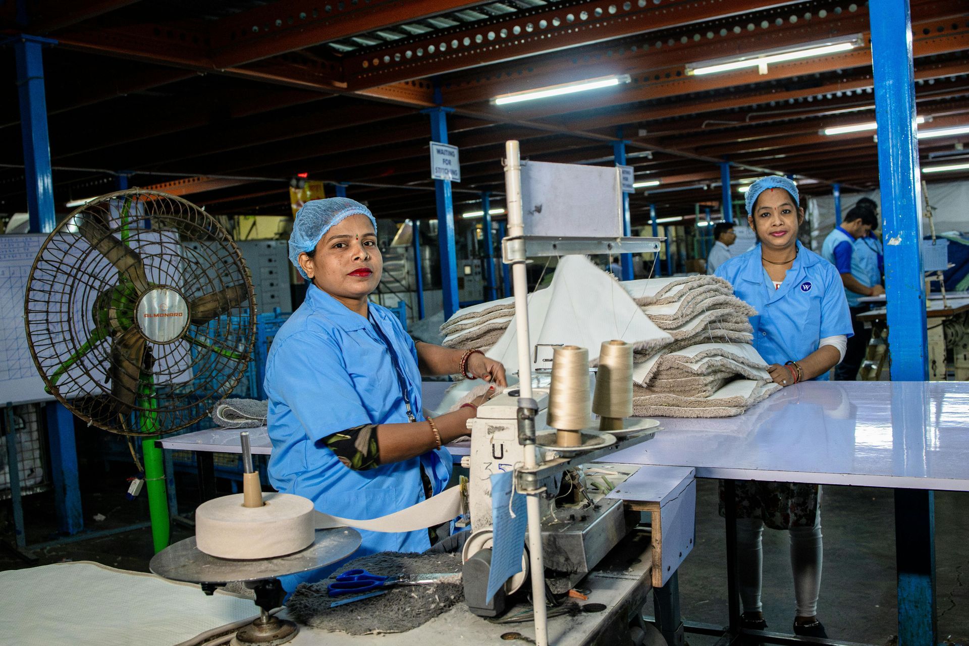 Couple reviewing a document with a person, indoors. They smile, looking at the person who is holding the document.