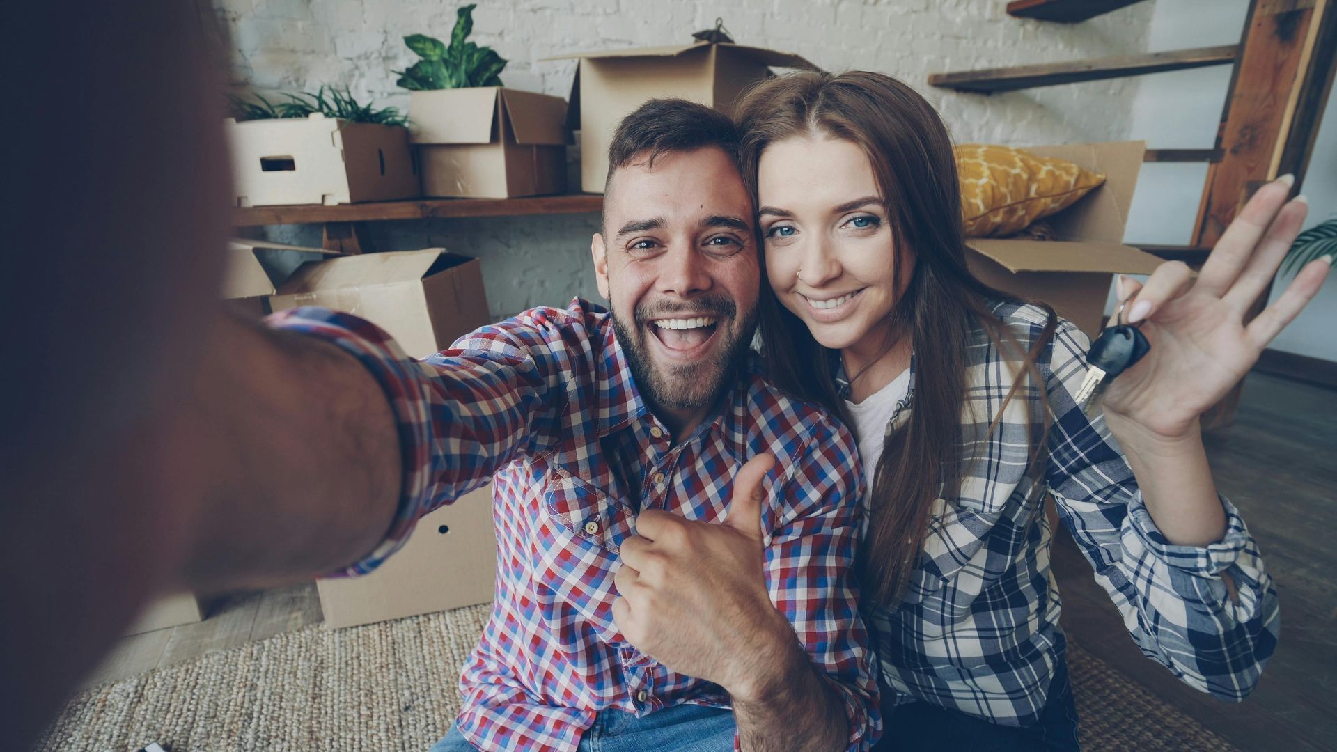 Couple reviewing a document with a person, indoors. They smile, looking at the person who is holding the document.